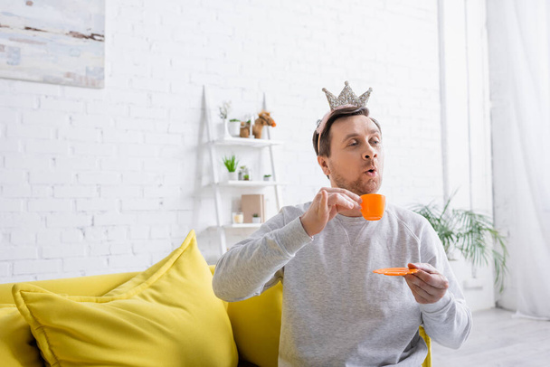 alegre hombre usando juguete corona mientras jugando príncipe en casa - Foto, imagen