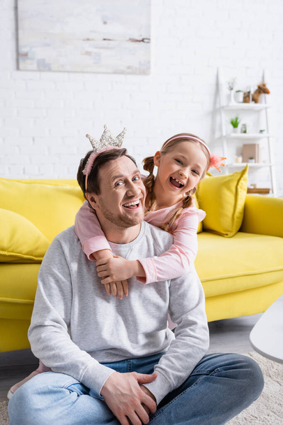izgatott lány átöleli boldog apa, miközben játszik herceg és hercegnő otthon - Fotó, kép
