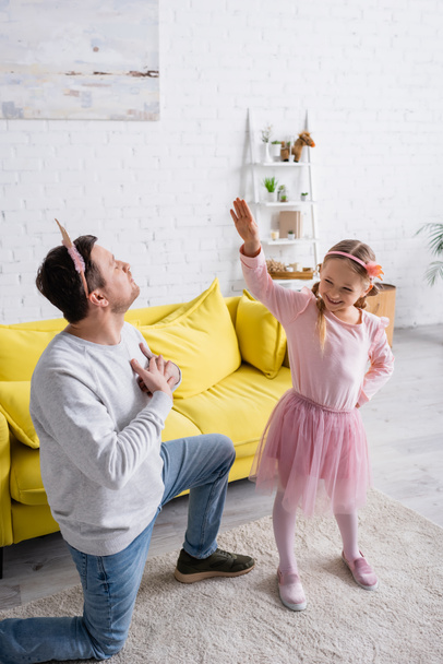 father in toy crown standing on knee and inviting daughter to dance - Foto, imagen