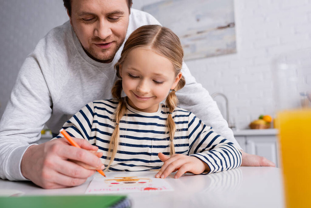 Gülümseyen adam keçeli kalemle kızının çizimine yardım ediyor - Fotoğraf, Görsel
