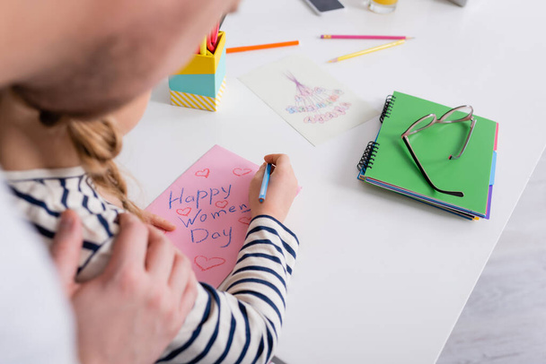 vista parcial de papá tocando hombro de hija dibujando feliz día de las mujeres tarjeta, borrosa primer plano - Foto, imagen
