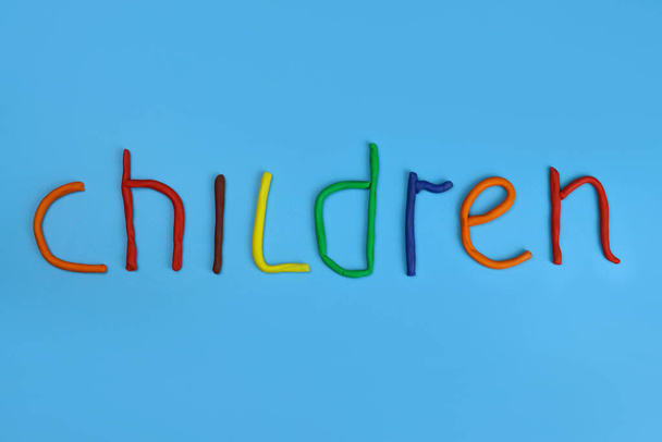λέξη παιδιά κατασκευασμένα από έγχρωμη πλαστελίνη σε μπλε φόντο - Φωτογραφία, εικόνα