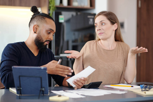 Homme sérieux montrant facture impayée à femme confus quand ils discutent budget familial - Photo, image