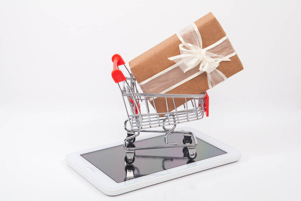 Tableta, dárkové balení a malý nákupní košík na stůl. koncept internetového nakupování. - Fotografie, Obrázek