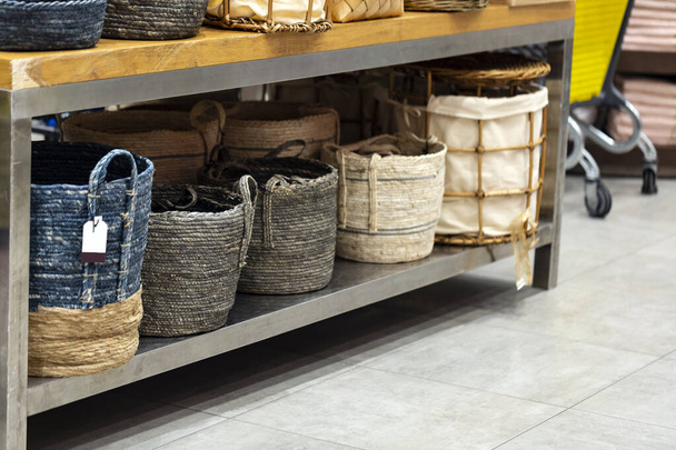 Laundry basket. Woven straw basket, container and boxes on a shelf in store. Bamboo weaving basket and brown Linen on shelf of rack background. Household decoration object made of natural eco material - Photo, Image