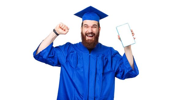 Дивовижний студент в блакитному халаті і святкування, тримаючи планшет з білим екраном
. - Фото, зображення