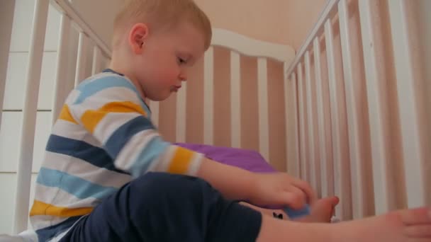 Chłopiec grać zabawki w łóżku - Materiał filmowy, wideo