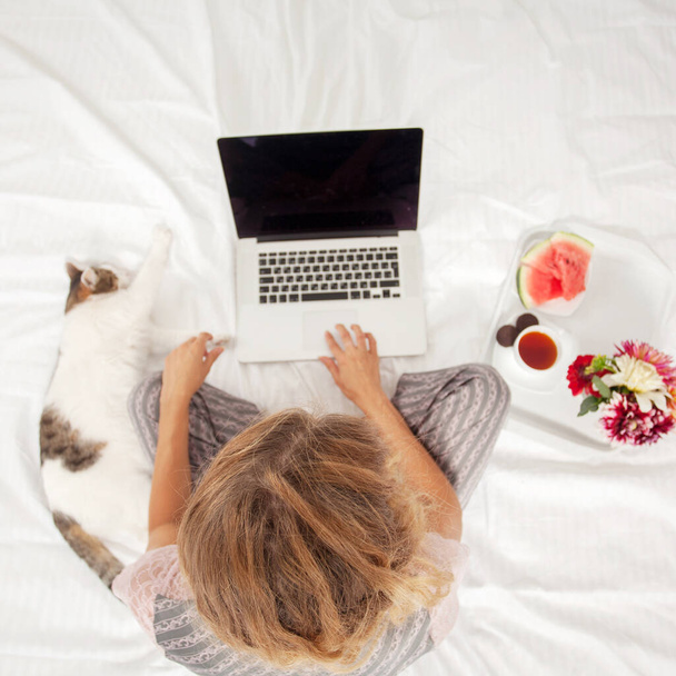 Young woman with laptop in the bed. Female freelancer - Foto, Imagen