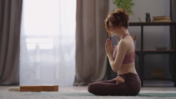 йога медитація вдома, доросла жінка сидить на підлозі в кімнаті, займаючи позицію лотоса, складаючи руки і розмірковуючи
 - Кадри, відео