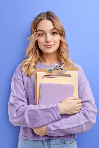 Shy teen student girl hold books isolated on pastel blue background studio portrait - Foto, imagen