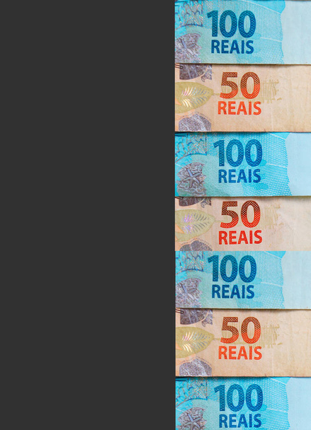 Бразильские деньги на черном фоне с копировальным пространством. Концепция экономики Бразилии. Вертикальное фото. - Фото, изображение