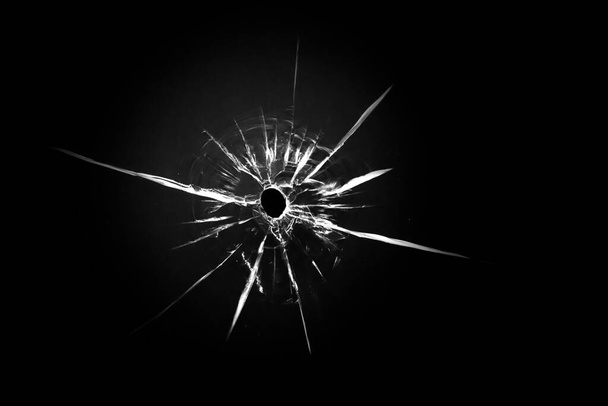 Rissige Textur auf schwarzem Hintergrund. Zerbrochene Glaskugel durch einen Schuss. - Foto, Bild