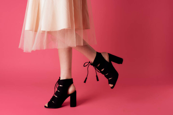 Female feet black fashionable heels shoes charm pink background - Foto, Bild