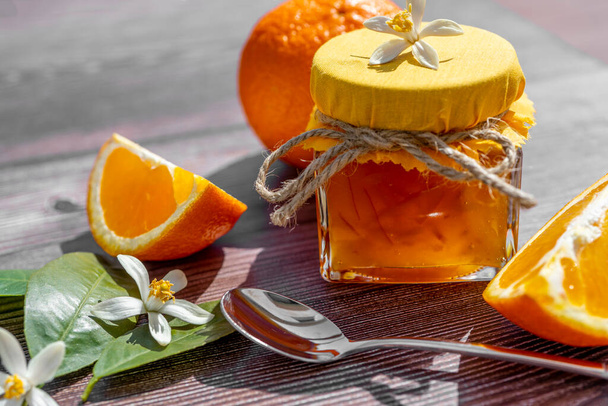 Παραδοσιακή σύνθεση μαρμελάδας πορτοκάλι με φρέσκα πορτοκαλί φρούτα σε ξύλινο φόντο. Νεκρή ζωή. Ελάχιστη έννοια τροφής. Σκληρή σκιά. Επίπεδη.  - Φωτογραφία, εικόνα