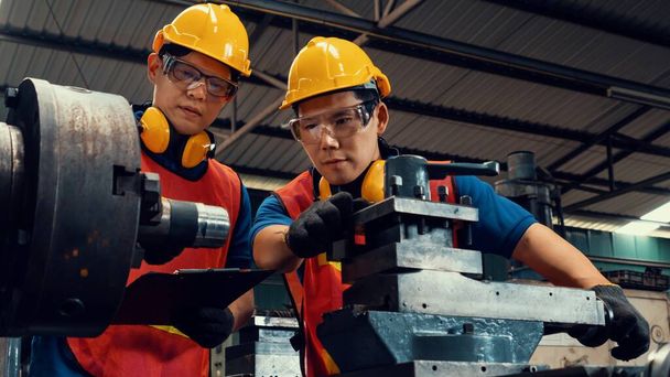 Группа квалифицированных заводских работников с использованием машинного оборудования в цехе - Фото, изображение