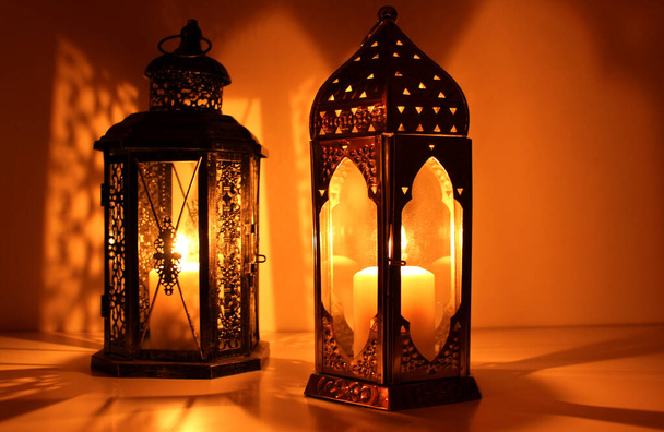 Ornamental Arabic lantern with burning candle glowing at night and glittering golden bokeh lights. Festive greeting card, an invitation for the Muslim holy month Ramadan Kareem. Dark background. - Photo, Image