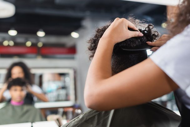 Peluquería afroamericana peinando cabello de cliente en capa  - Foto, Imagen
