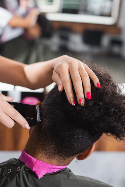 Парикмахер стрижет волосы африканского американца в салоне  - Фото, изображение