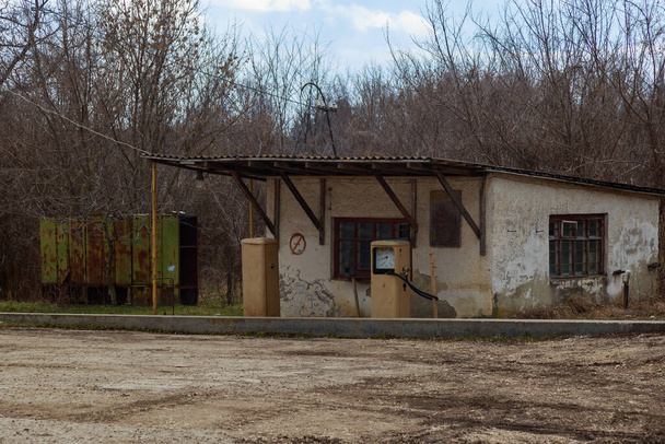 Egy régi elhagyatott analóg benzinkút. A természet által meghódított ipari övezet vagy termelési terület. Háttér - Fotó, kép
