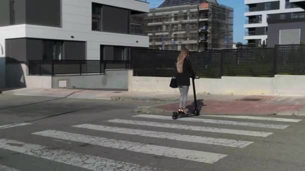 Femme méconnaissable traversant la rue en scooter électrique - Séquence, vidéo
