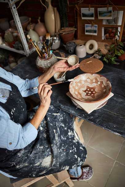 Художница-керамистка рисует на глиняной чаше в мастерской - Фото, изображение