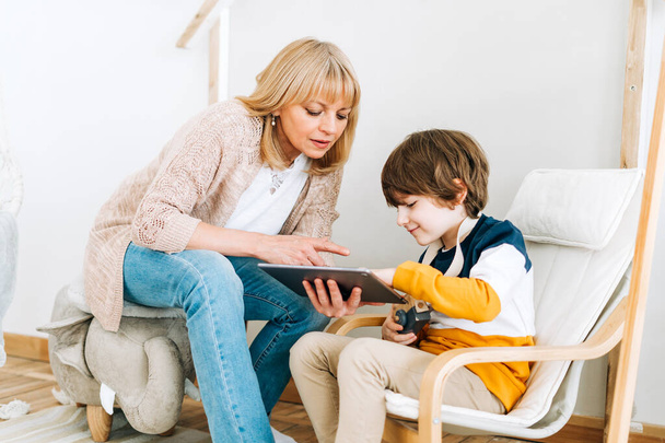 Mother with son in childrens room, looking at tablet  - Photo, Image