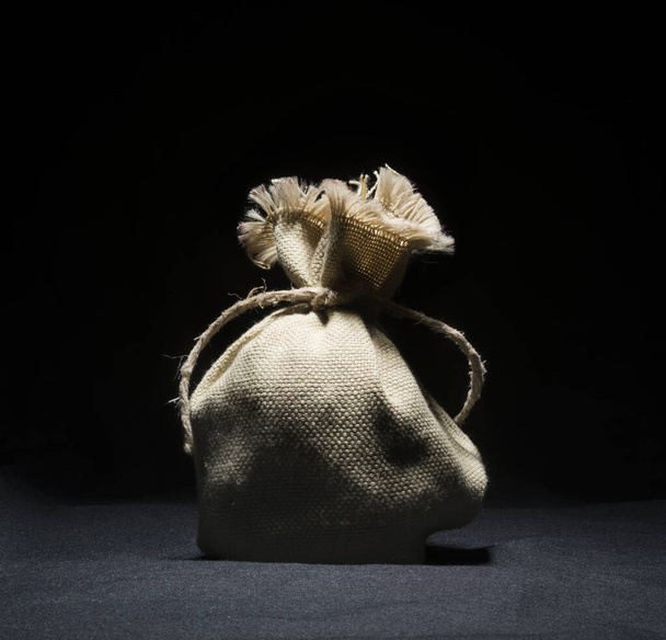 Μικρή τσάντα γιούτα με σχοινί κάνναβης σε μαύρο φόντο ύφασμα - Φωτογραφία, εικόνα