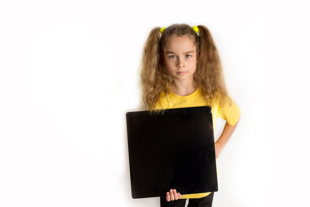 Egy sárga T-shot-os lány fekete négyzetet tart a feliratához. Fehér háttér. Stúdió fotózás. - Fotó, kép