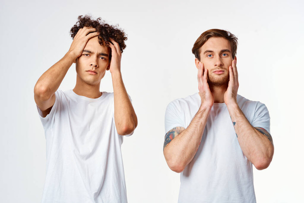 двое мужчин в белых футболках держат свои головы недовольными эмоциями - Фото, изображение