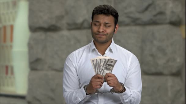 Dissatisfied businessman in handcuffs holding bills of money. - Footage, Video