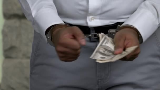 Бизнесмен в наручниках держит взятку. - Кадры, видео