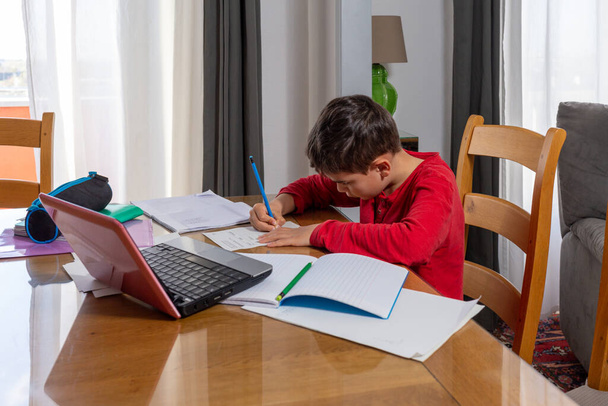 αγόρι κάνει τα μαθήματά του, ενώ κλειδώνει, μελετώντας εξ αποστάσεως - Φωτογραφία, εικόνα