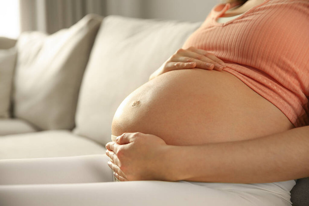 Pregnant woman touching her belly indoors, closeup - Foto, immagini