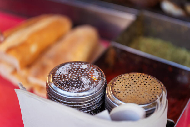Κηλίδες από βάζα μπαχαρικών κοντά. Αλατοπίπερο με μεταλλικό καπάκι στο φόντο τούρκικου γρήγορου ψωμιού - Φωτογραφία, εικόνα