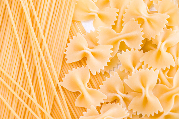 Dry raw pasta Farfalle and spaghetti on the white background, natural light - Фото, изображение