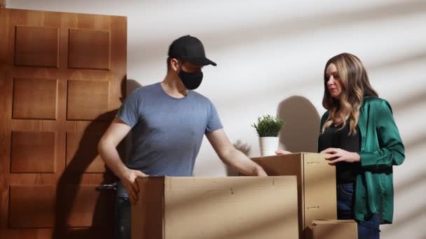 Gemaskerde postbode haalt kartonnen dozen op uit het appartement. - Video