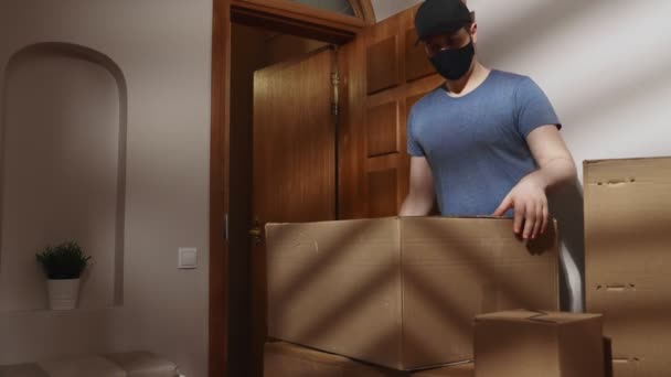 Zamaskowany mężczyzna odbiera kartonowe pudła z mieszkania.. - Materiał filmowy, wideo