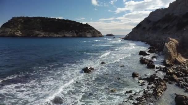 Spostandosi sopra una costa rocciosa in una giornata ondulata con e isola sullo sfondo - Filmati, video