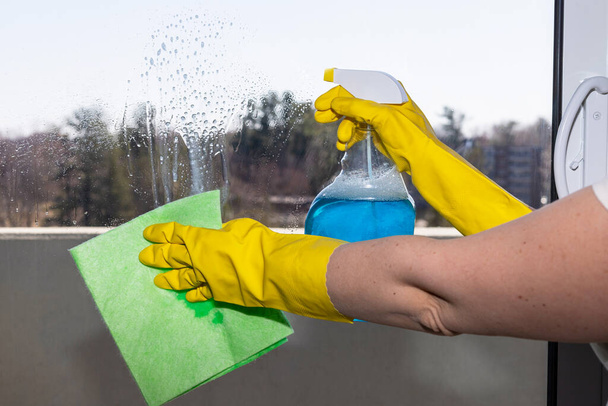 Ręce kobiety w rękawiczkach czyszczące okno drzwi balkonowe sprayem do detergentów i tkaniną - Zdjęcie, obraz