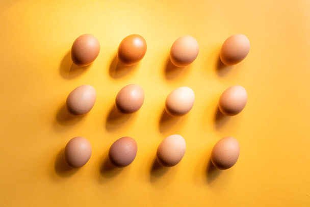 Group of fresh eggs aligned on yellow background. Easter concept. Background, pattern - Fotografie, Obrázek