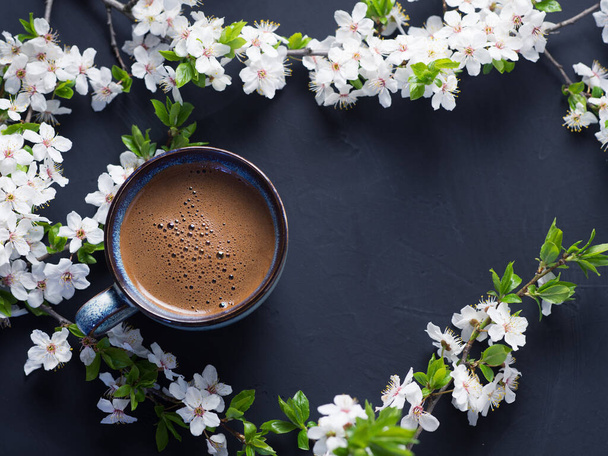 香り高い淹れたてのコーヒーと春の桜の花の枝のカップ - 写真・画像