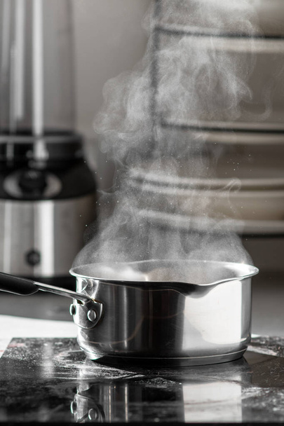 Agua hirviendo con vapor en una olla sobre una estufa eléctrica en la cocina.  - Foto, imagen