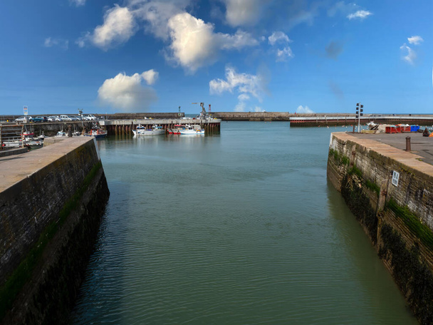 Port-en-Bessin-Huppain, Francia, marzo de 2021. Imagen del canal de navegación hacia el mar en un pintoresco pueblo de Normandía - Foto, imagen