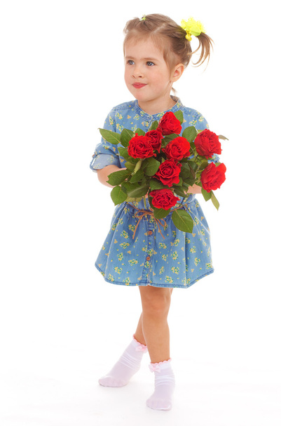 charming little girl holding a bouquet of red roses. - Zdjęcie, obraz