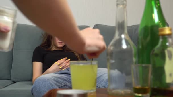 een vrouw lijdt aan een kater, ze drinkt pijnstillers in een glas water - Video