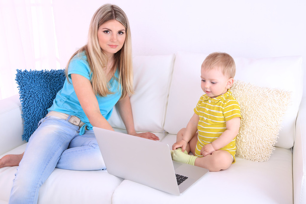 Mother and son with laptop on sofa at home - 写真・画像
