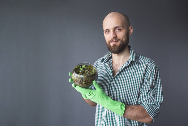 Флораріум Скляна ваза з соковитими. бородатий чоловік показує вазу з сукулентами і мохом
. - Фото, зображення