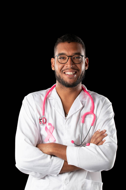 dark skin doctor with pink stethoscope and pink awareness breast cancer ribbon, on a black background. - Photo, Image