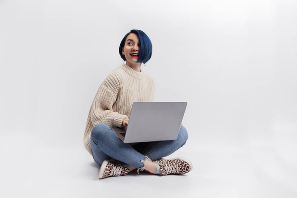 A woman sitting on the floor and holding a laptop. Isolated - Photo, Image