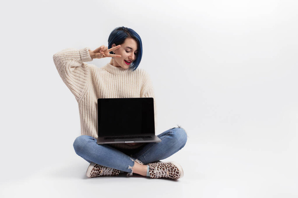 Kobieta siedząca na podłodze i trzymająca laptopa. Izolacja - Zdjęcie, obraz